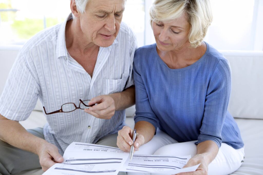 senior couple looking at papers while sitting on a couch