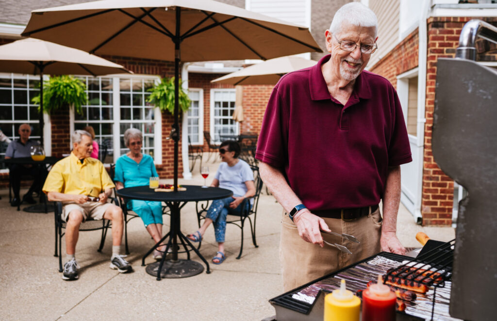 Man grilling out with friends in the background